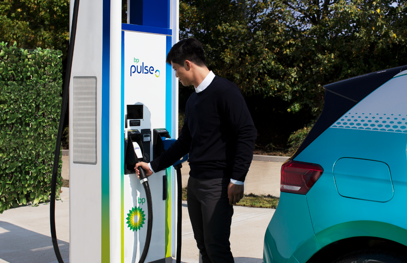man charging electric vehicle with bp pulse fast charger